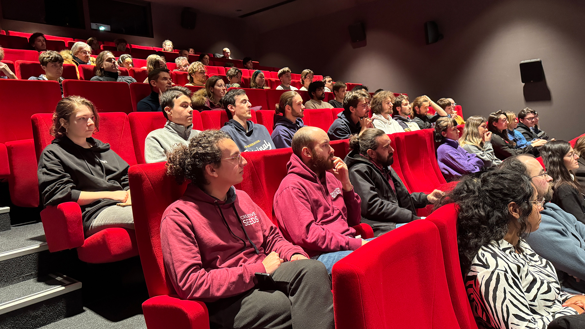 Fauteuils d'auditorium occupés par public lors événement au Lieu Creative Seeds