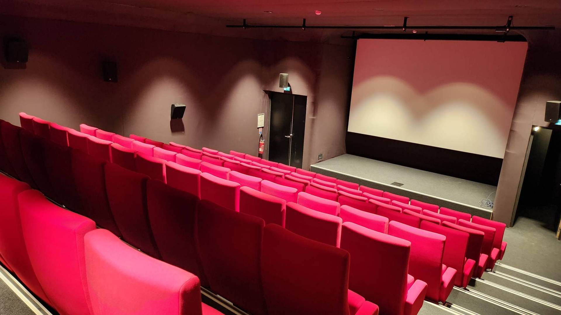 Vue arrière fauteuils auditorium avec grand écran de projection allumé